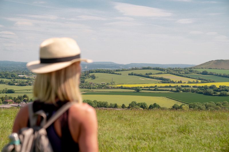 Alexia looking out over green fields and hills on a summer walk