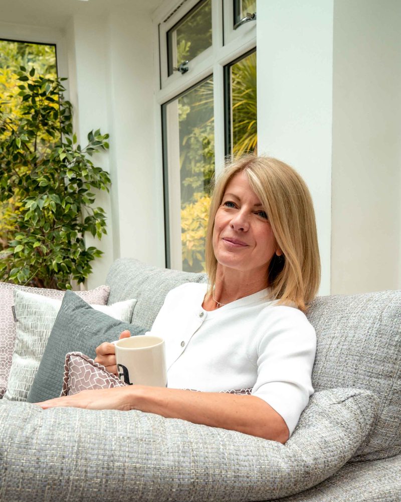 Alexia Bylett sitting on a sofa holding a mug