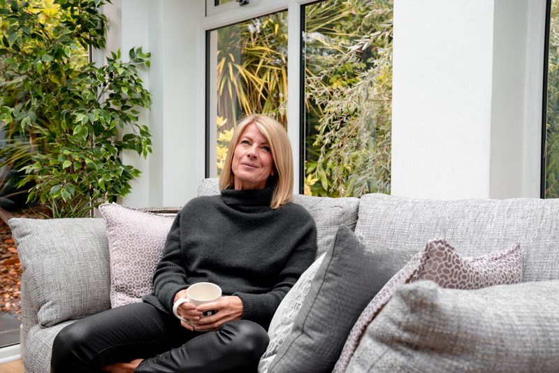 Alexia Bylett relaxing on a sofa with a mug of tea